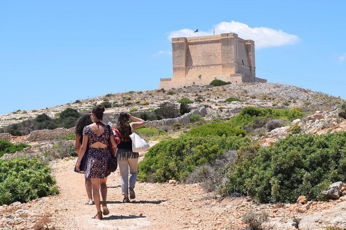 Tres mujeres caminando por un camino de tierra con un castillo al fondo