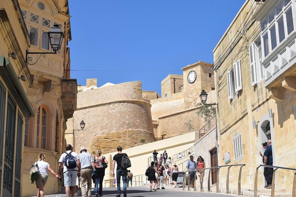 Un grupo de personas caminando por una calle con una torre de reloj.
