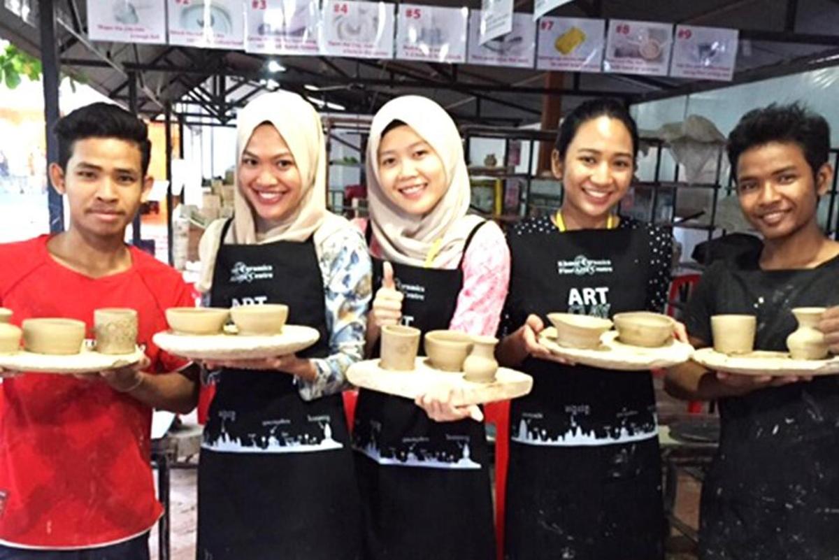 a group of four people holding plates of pottery