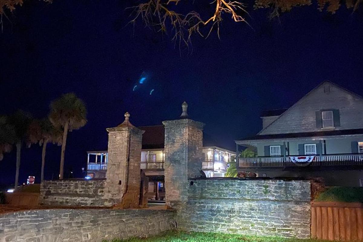 a large house at night with a stone wall
