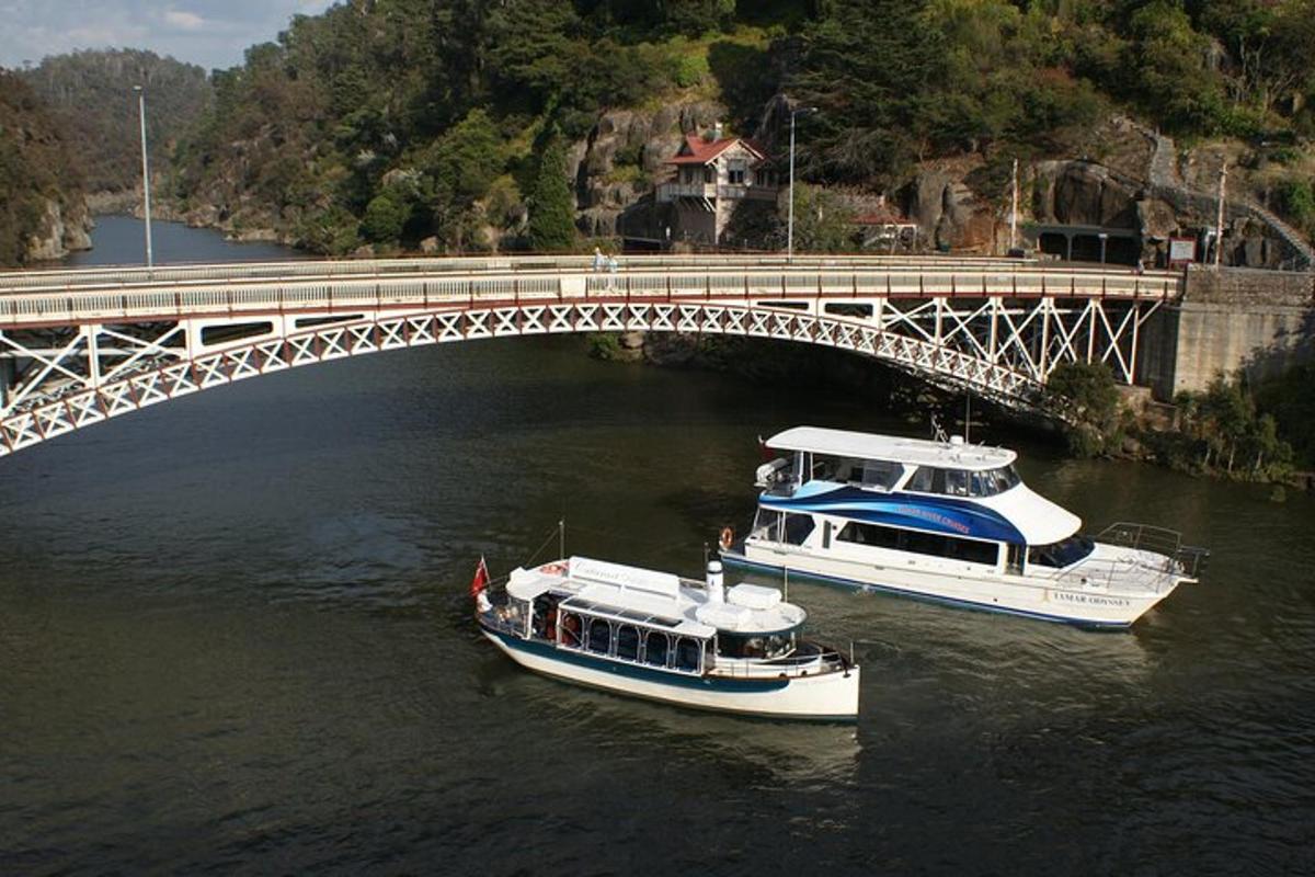 two boats in the water under a bridge