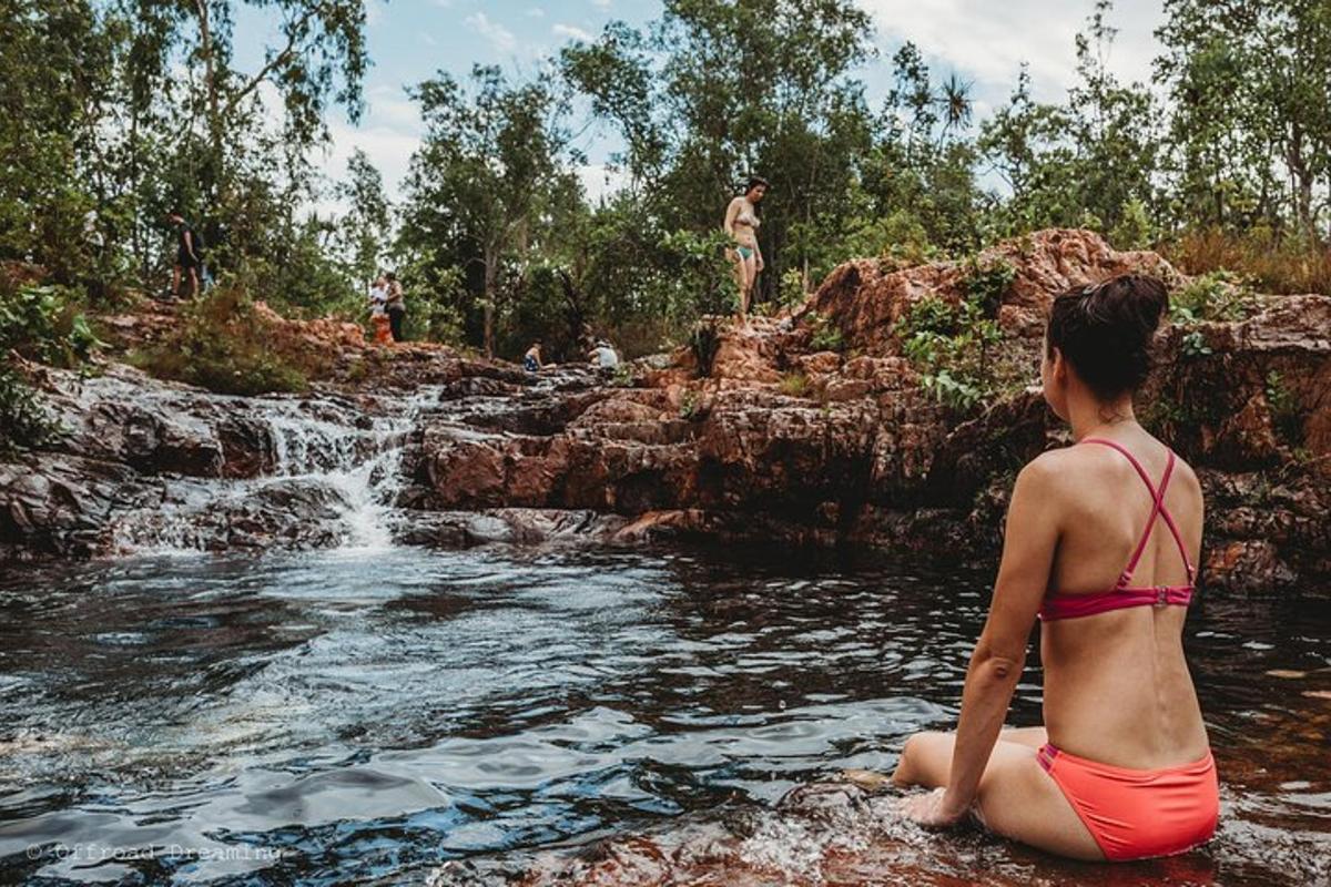 een vrouw zittend in het water voor een waterval
