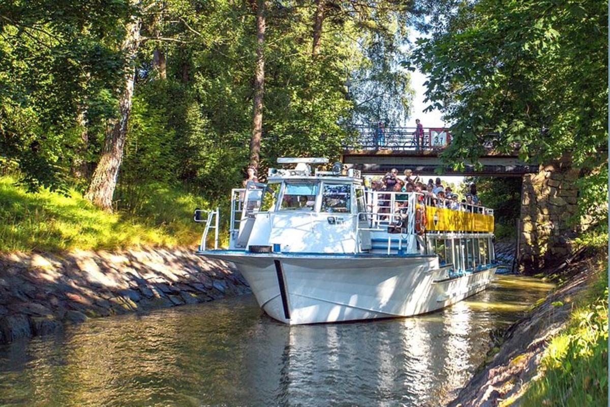 a boat on a river with people on a bridge