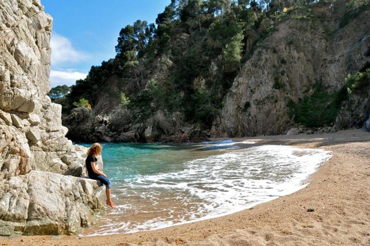 uma mulher sentada em uma rocha na praia