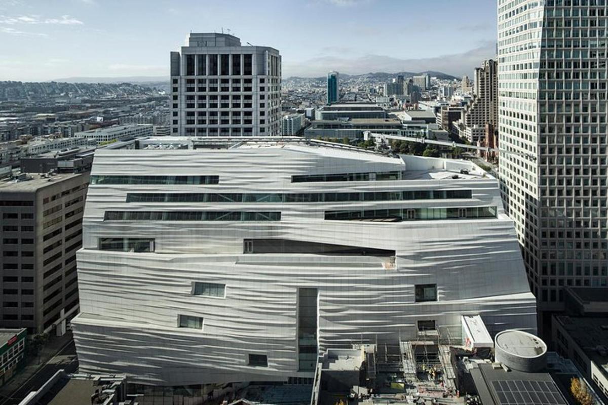 a large white building in a city with tall buildings