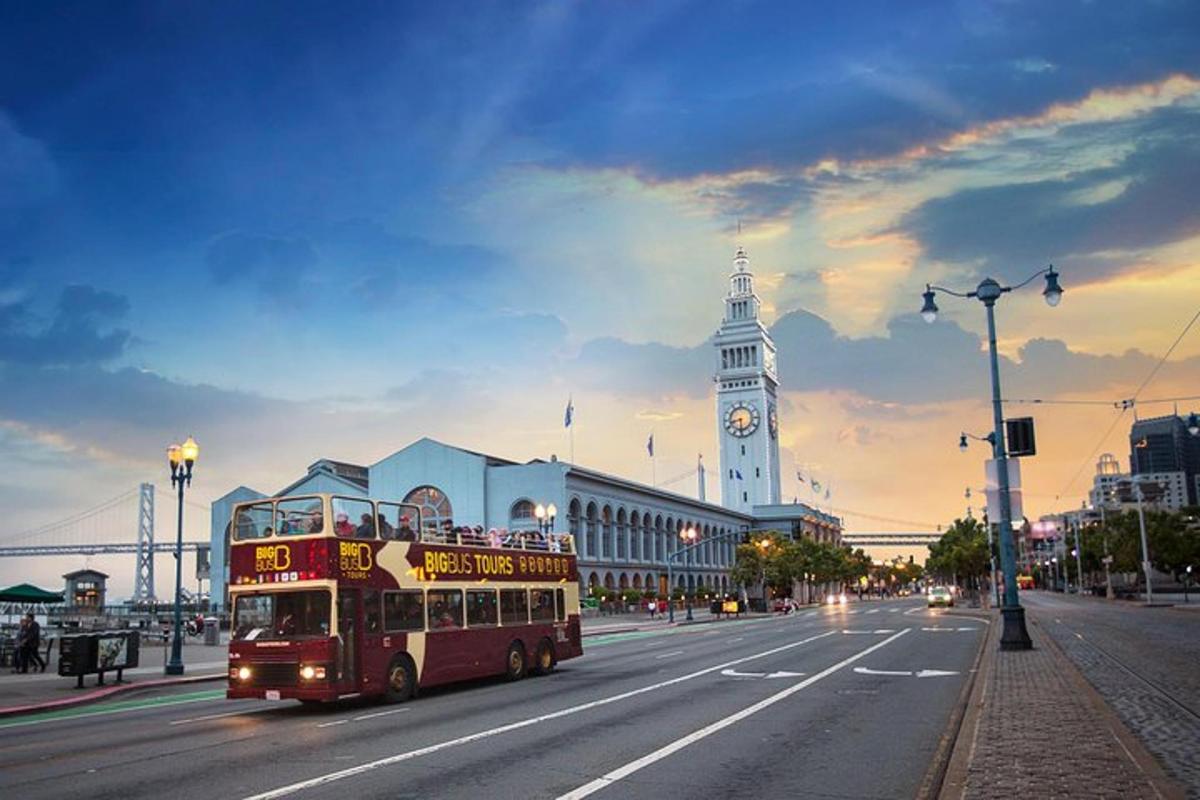 a double decker bus driving down a street with a clock tower