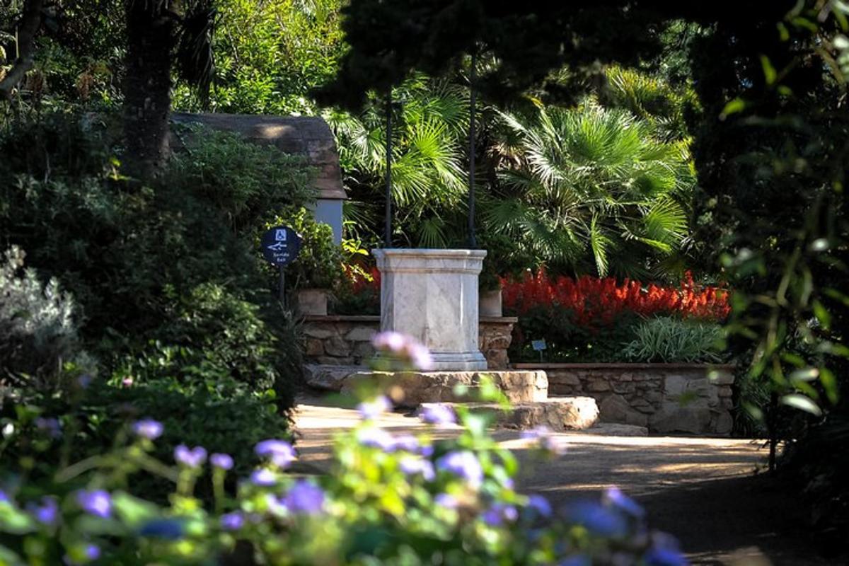 Un jardín con flores y una estatua en el medio.