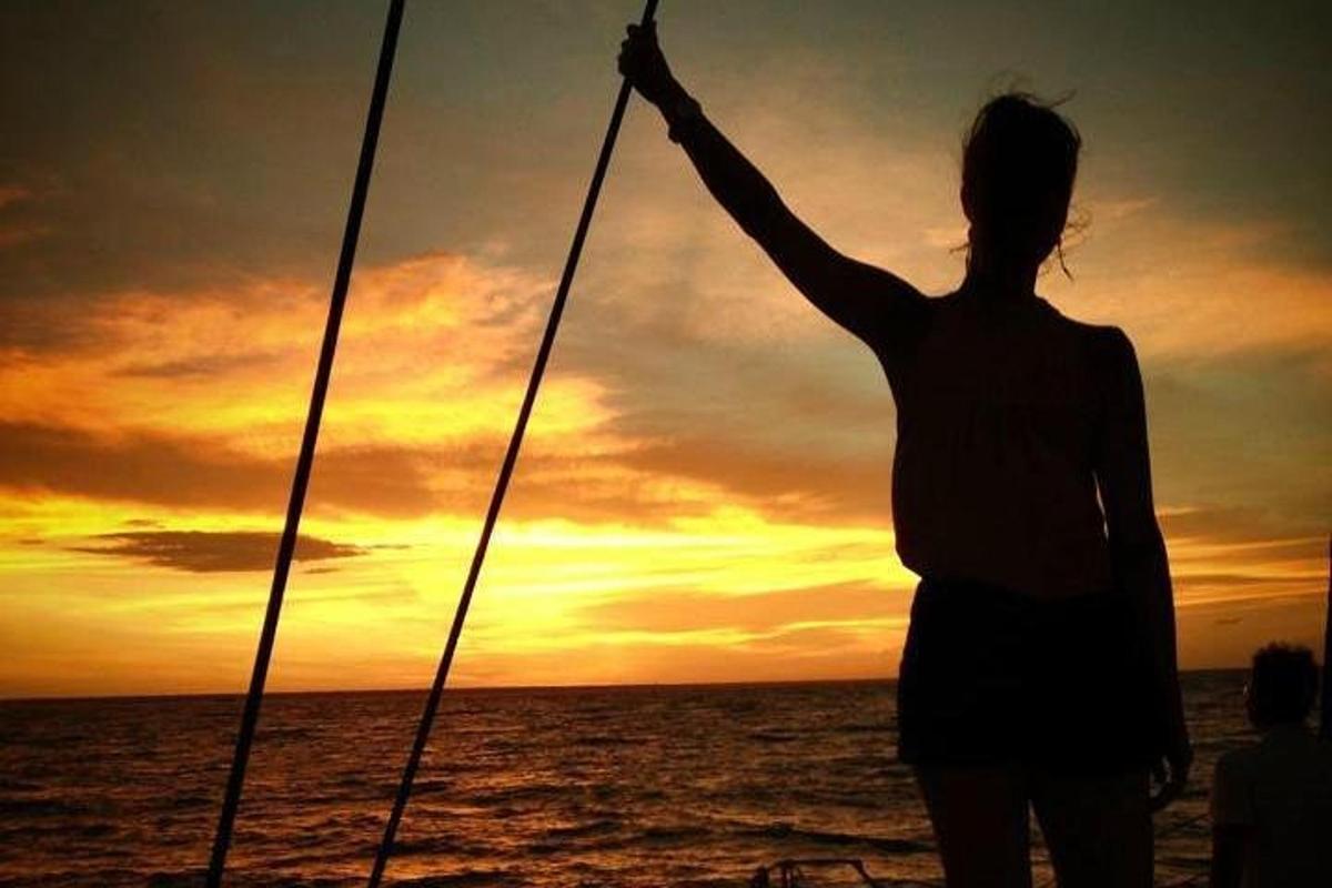 a woman standing on a boat at sunset