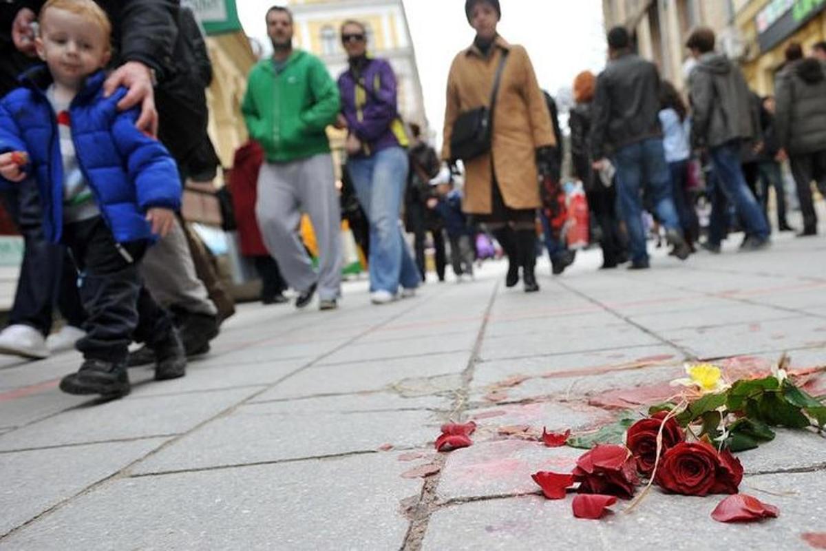 un ragazzo sta guardando un mucchio di rose su un marciapiede