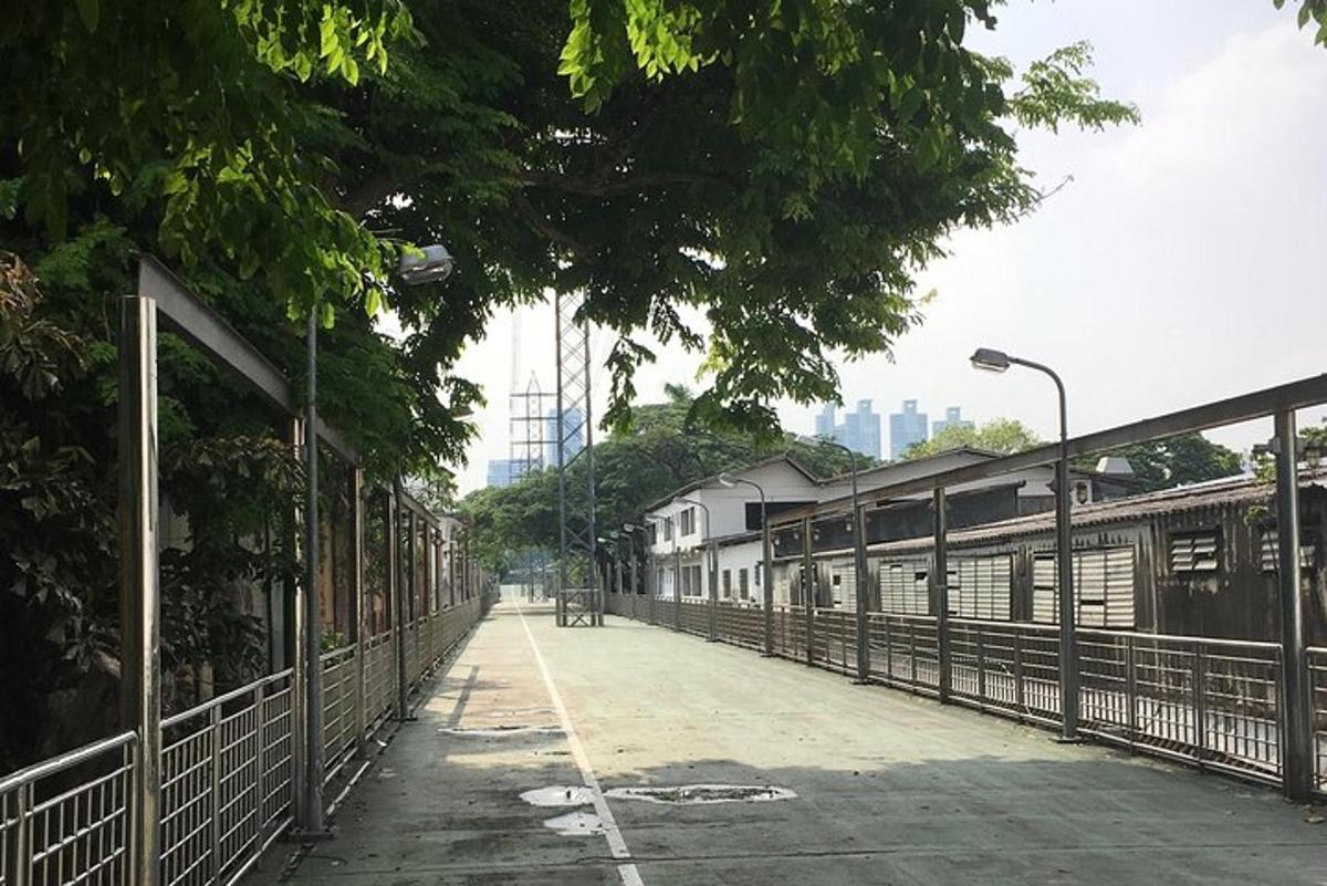una strada vuota con una recinzione, alberi ed edifici