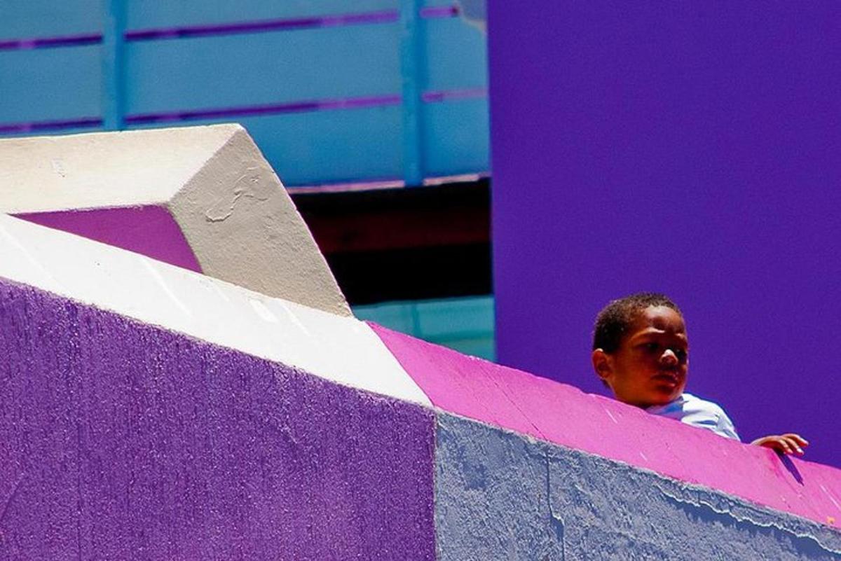 Un hombre parado detrás de una pared morada y blanca.