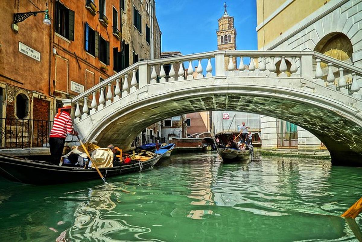 Un puente sobre un canal con góndolas en el agua.