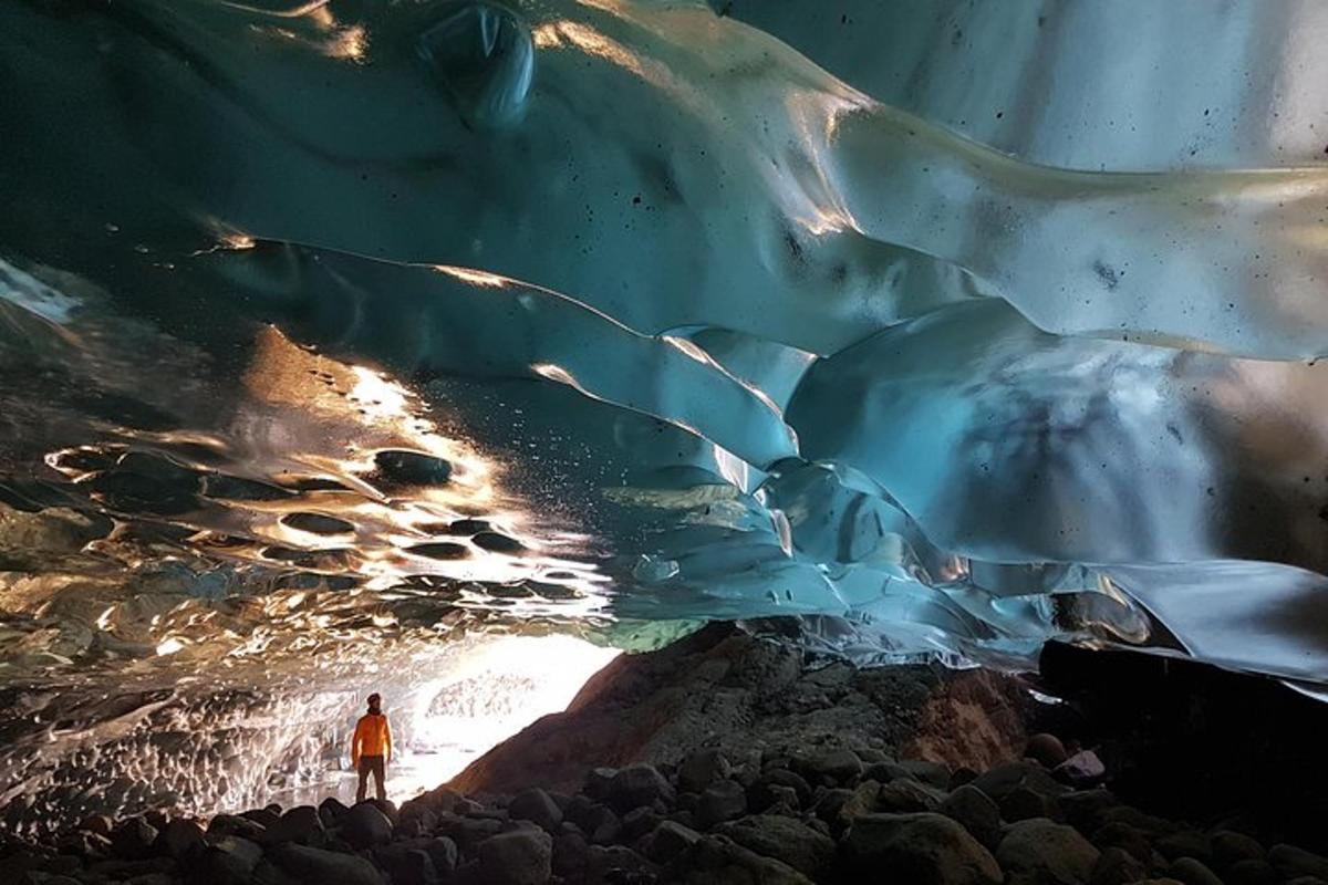 a man stands in front of an ice cave