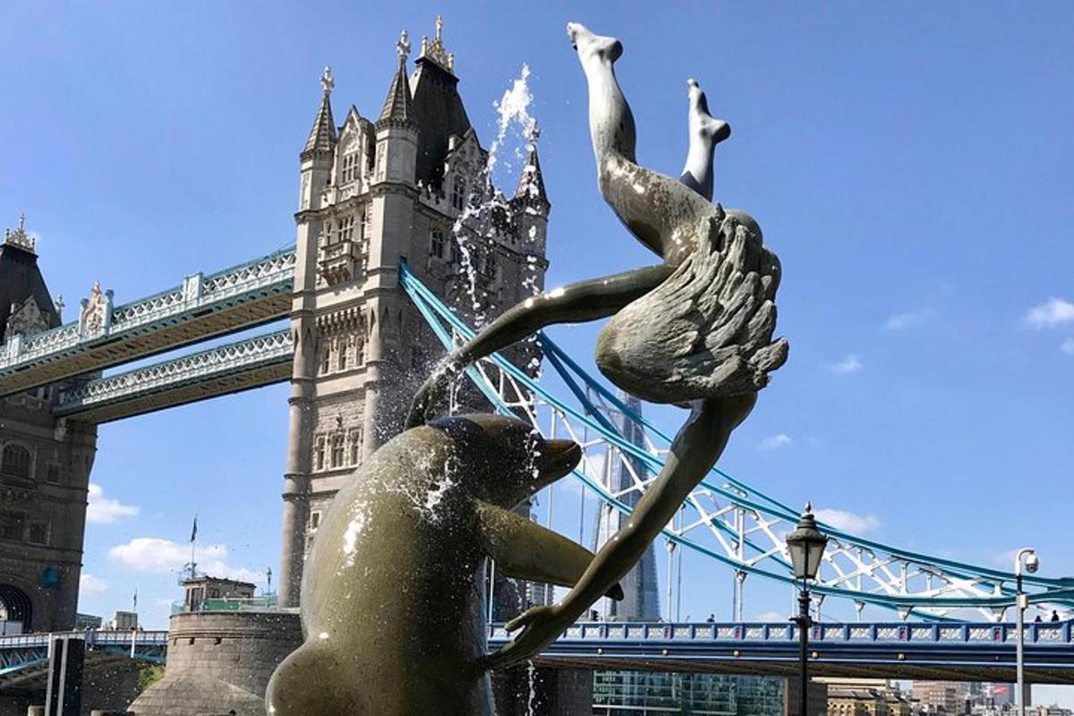 una statua di una donna e due cigni davanti a un ponte