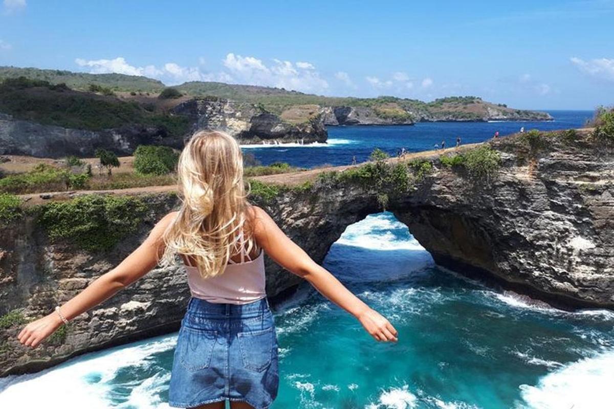 a woman standing in front of an arch in the ocean