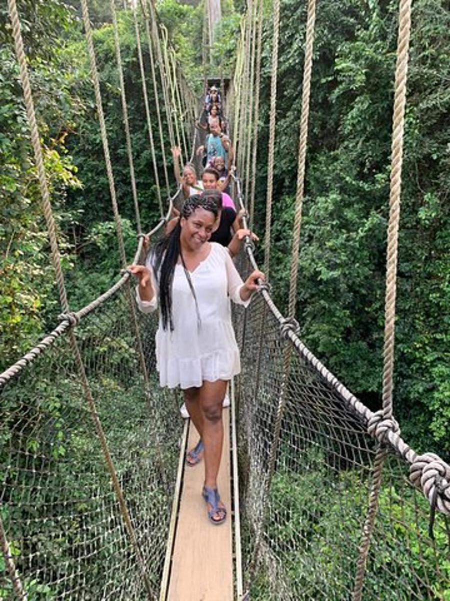 Una mujer caminando por un puente colgante en la jungla.