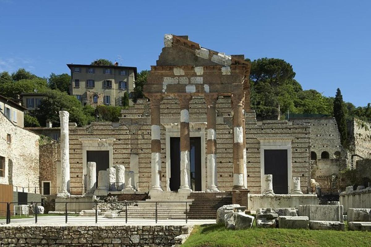um edifício antigo com colunas e uma casa ao fundo