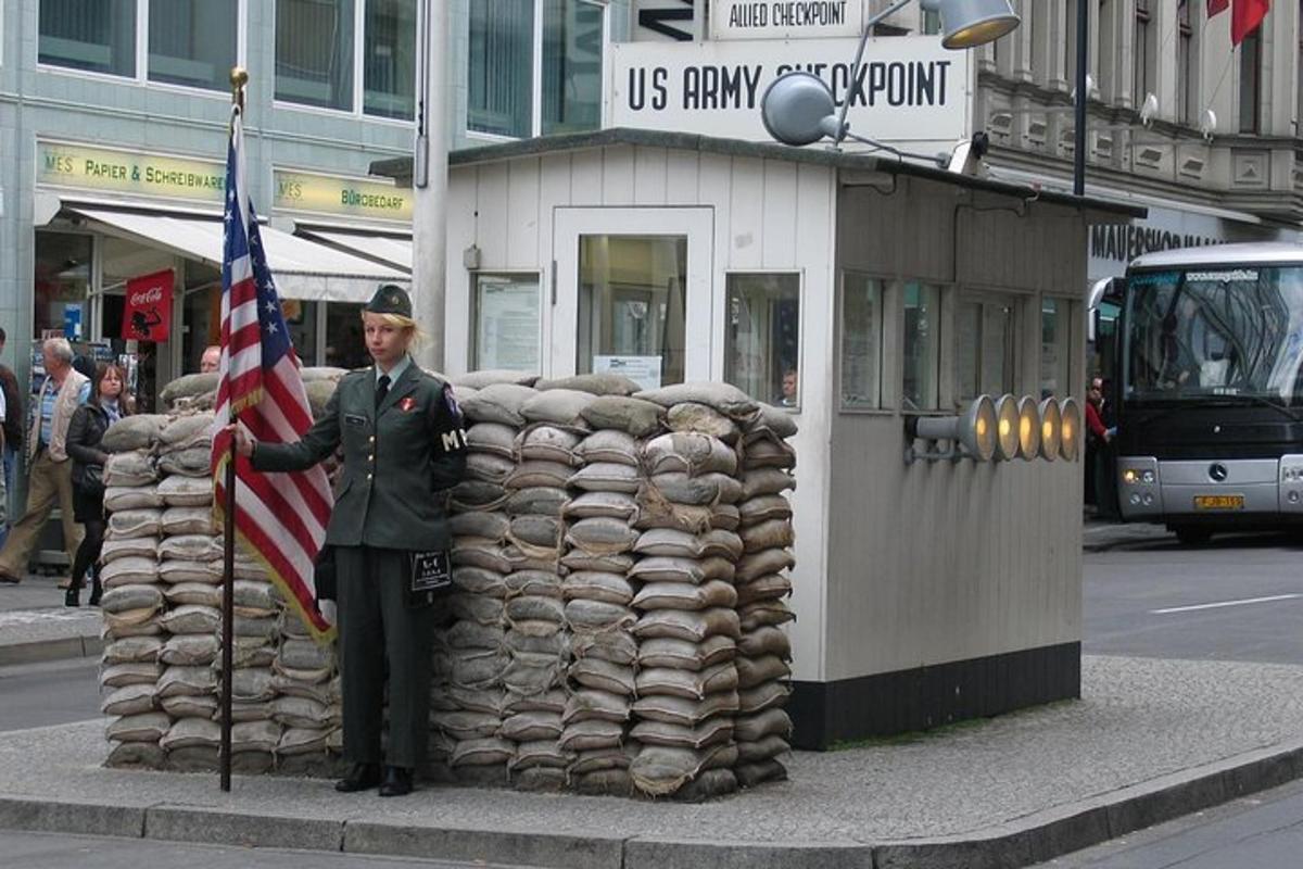 un uomo in uniforme che tiene una bandiera americana accanto a un edificio