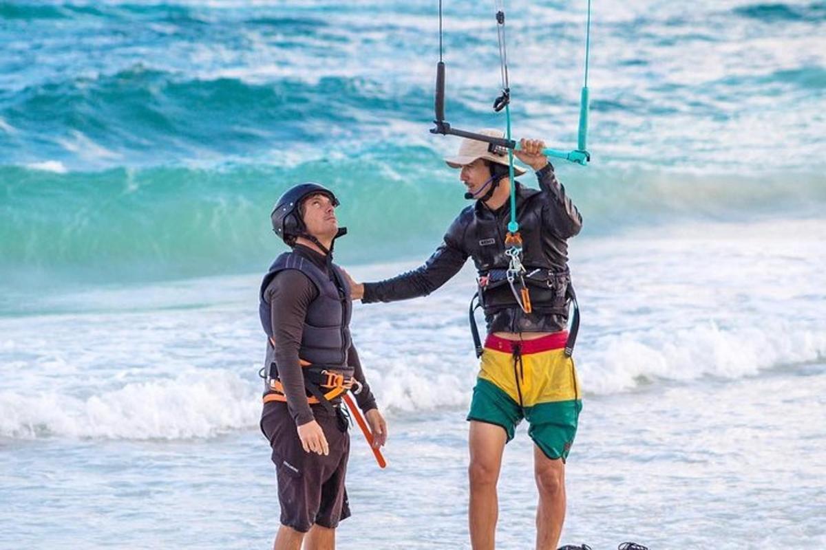 two men are standing on the beach holding onto a handle