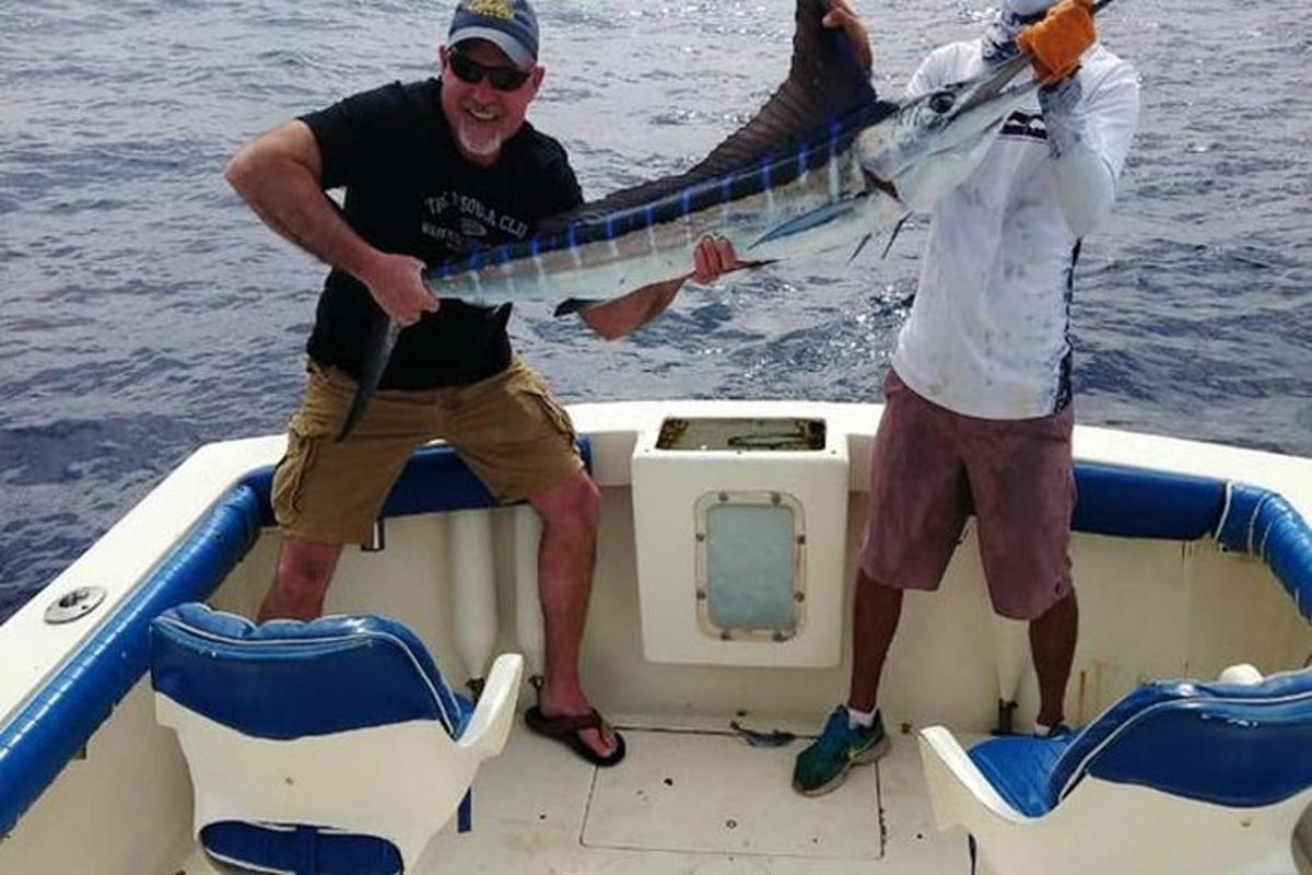 dalawang lalaking nakatayo sa isang bangka na may hawak na isda