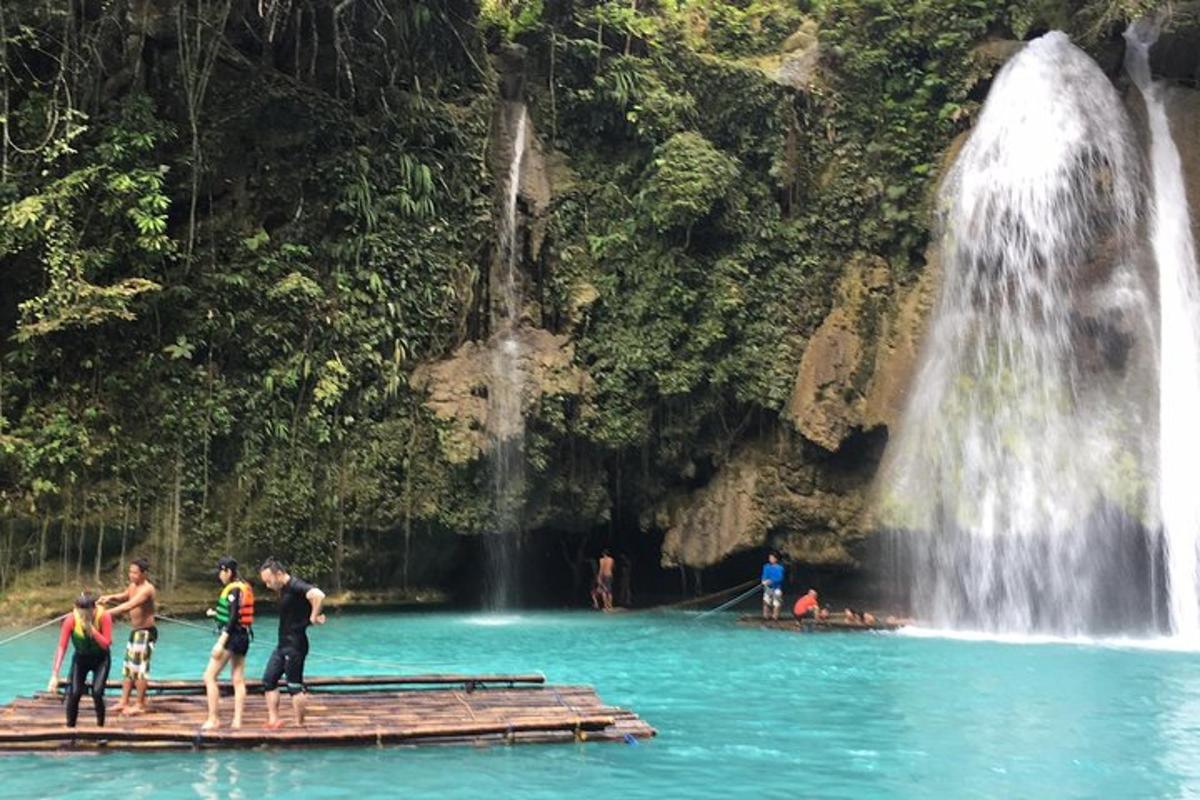 um grupo de pessoas em pé em uma jangada em frente a uma cachoeira