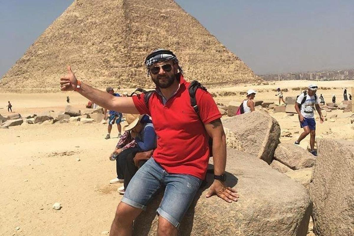um homem sentado em algumas rochas em frente às pirâmides