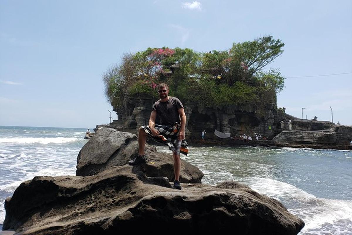 un uomo seduto su una roccia nell'oceano