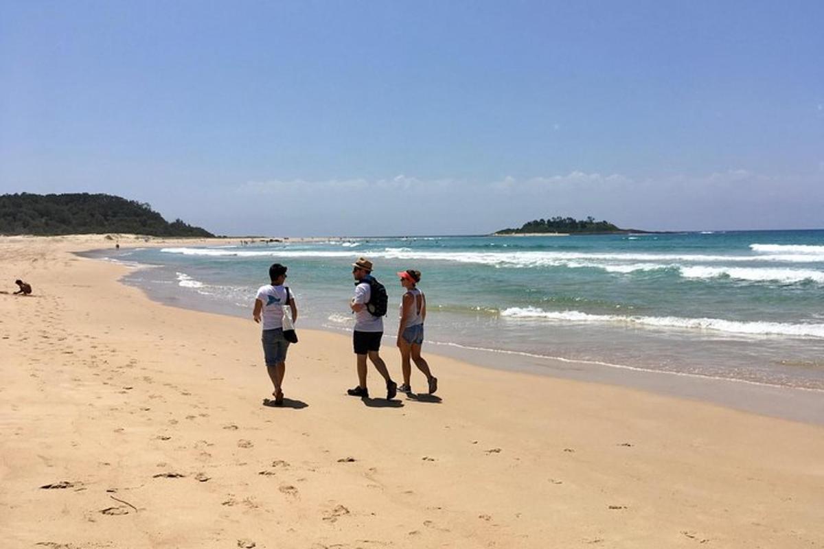three people walking on a beach near the ocean