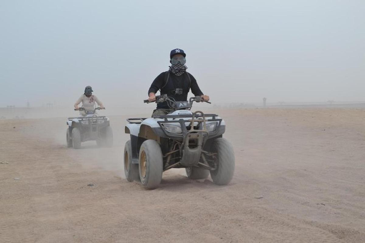 dues persones que condueixen quads al desert