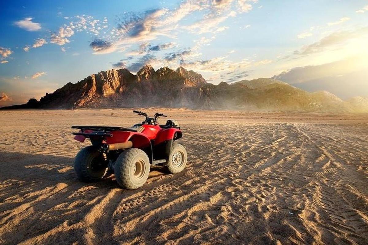 Un vehículo todo terreno rojo estacionado en la arena del desierto.