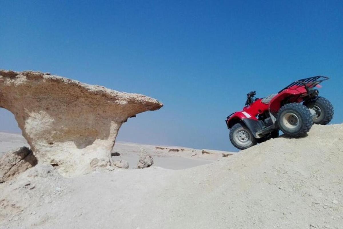 Un vehículo todo terreno rojo en la arena del desierto.