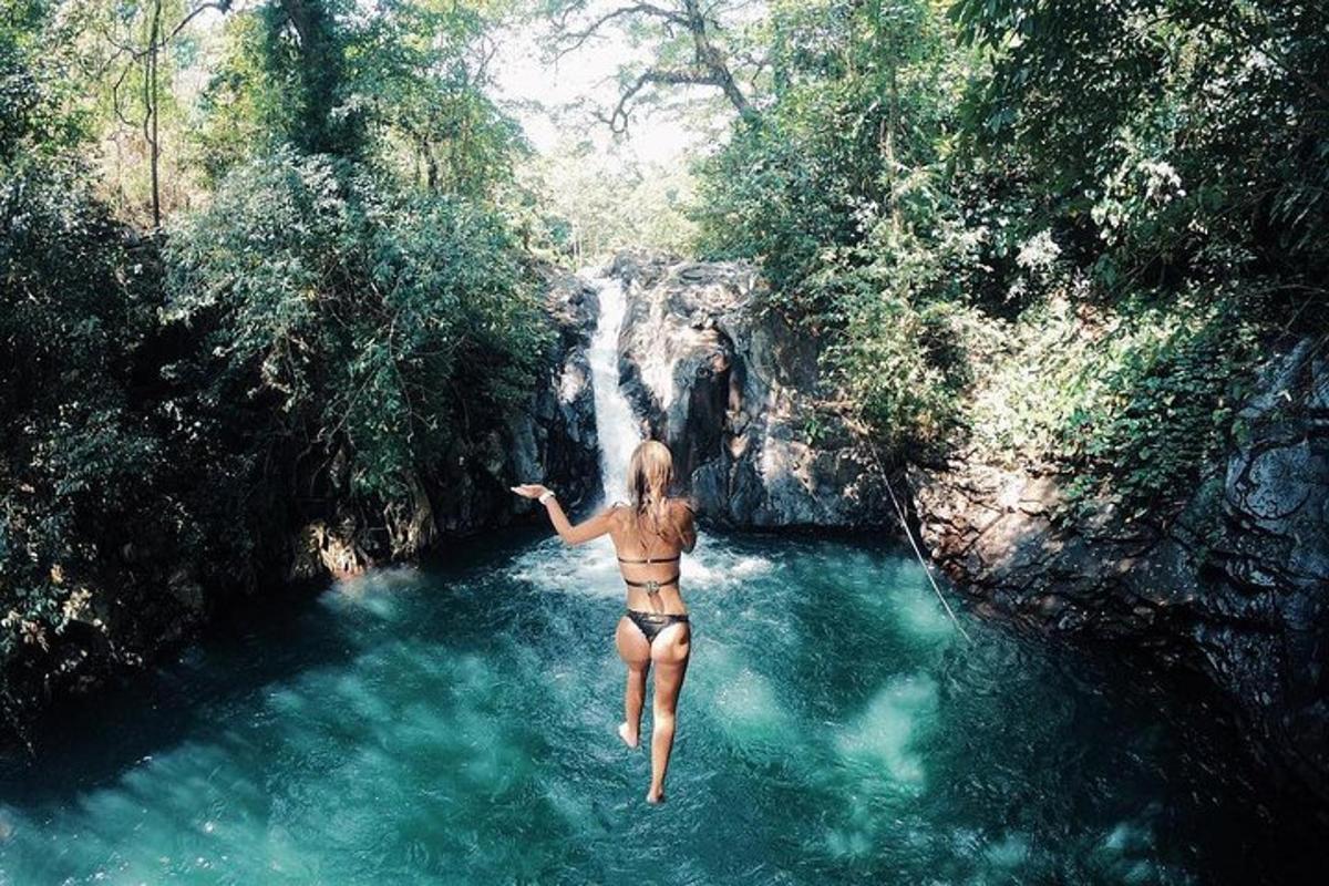 seorang wanita berbikini melompat ke dalam air terjun