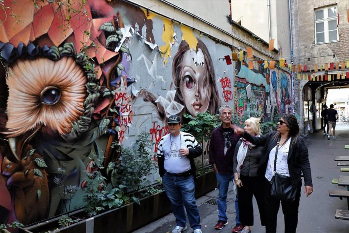 egy csoport ember áll egy graffitivel borított fal előtt