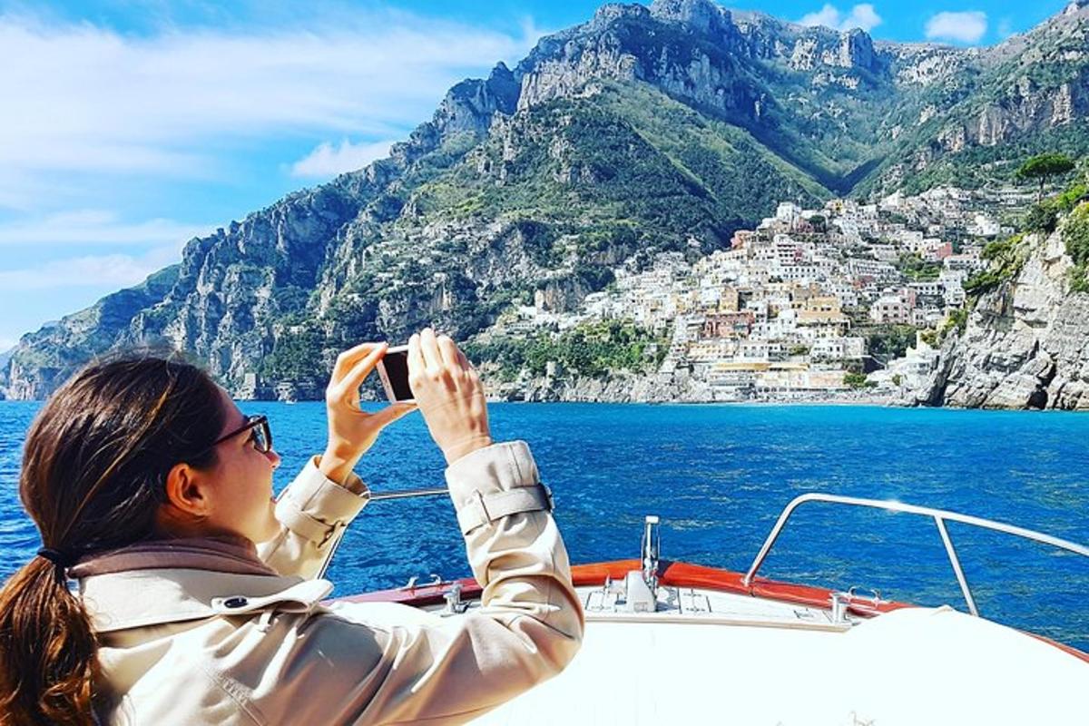 una donna che scatta una foto della costiera amalfitana da una barca