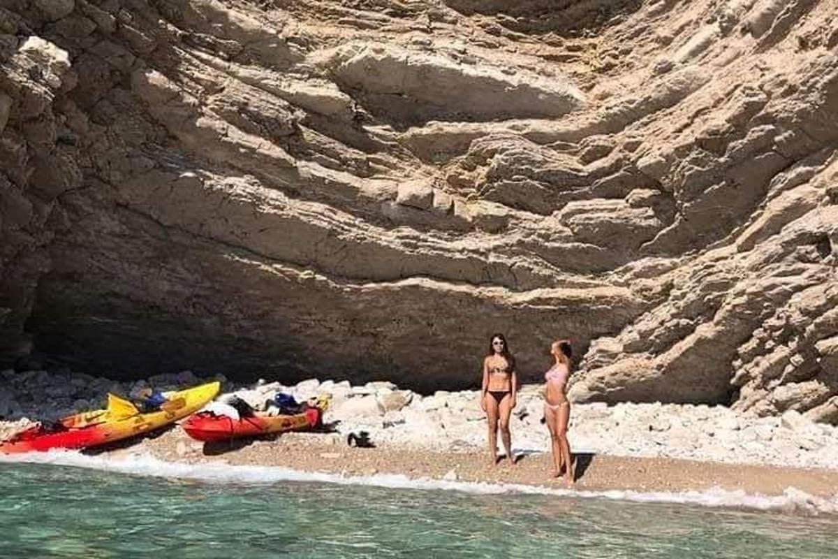 duas mulheres em pé na praia perto da água