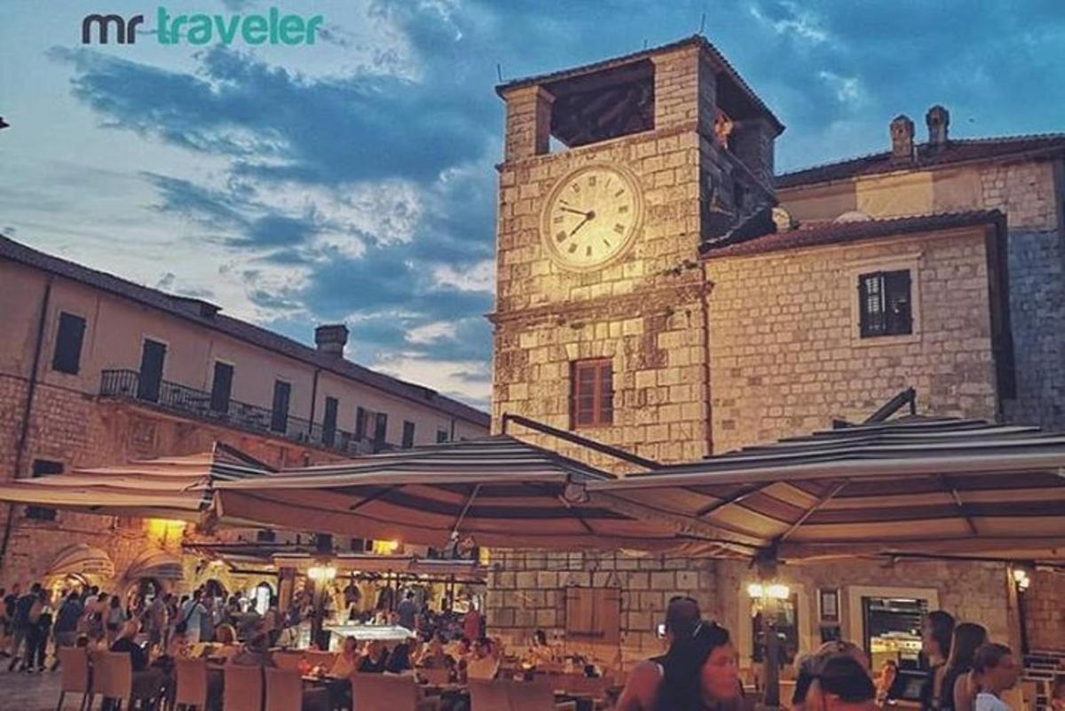 a clock tower on a building with people sitting at tables