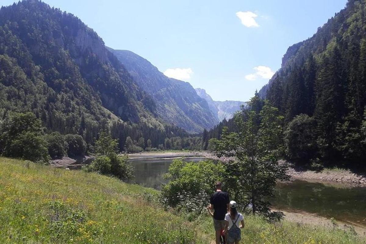 two people standing on a hill looking at a river