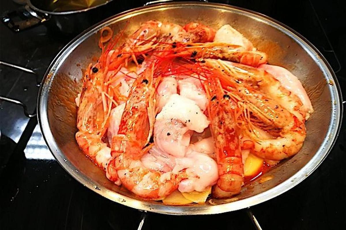 Una sartén llena de camarones y verduras en una estufa