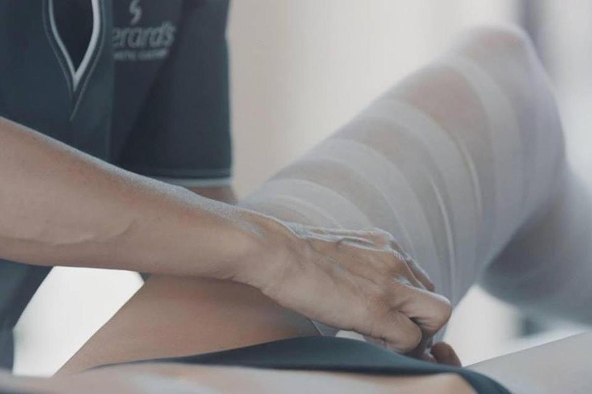 a woman getting her arm wrapped in a roll of toilet paper