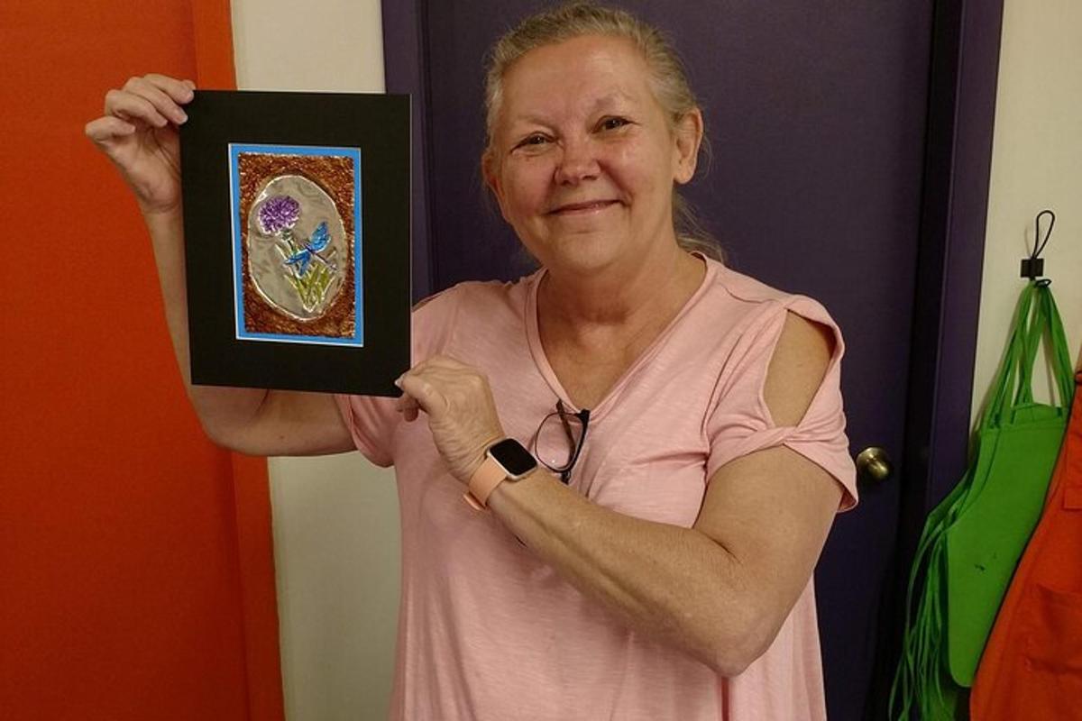 a woman holding up a picture in front of a mirror
