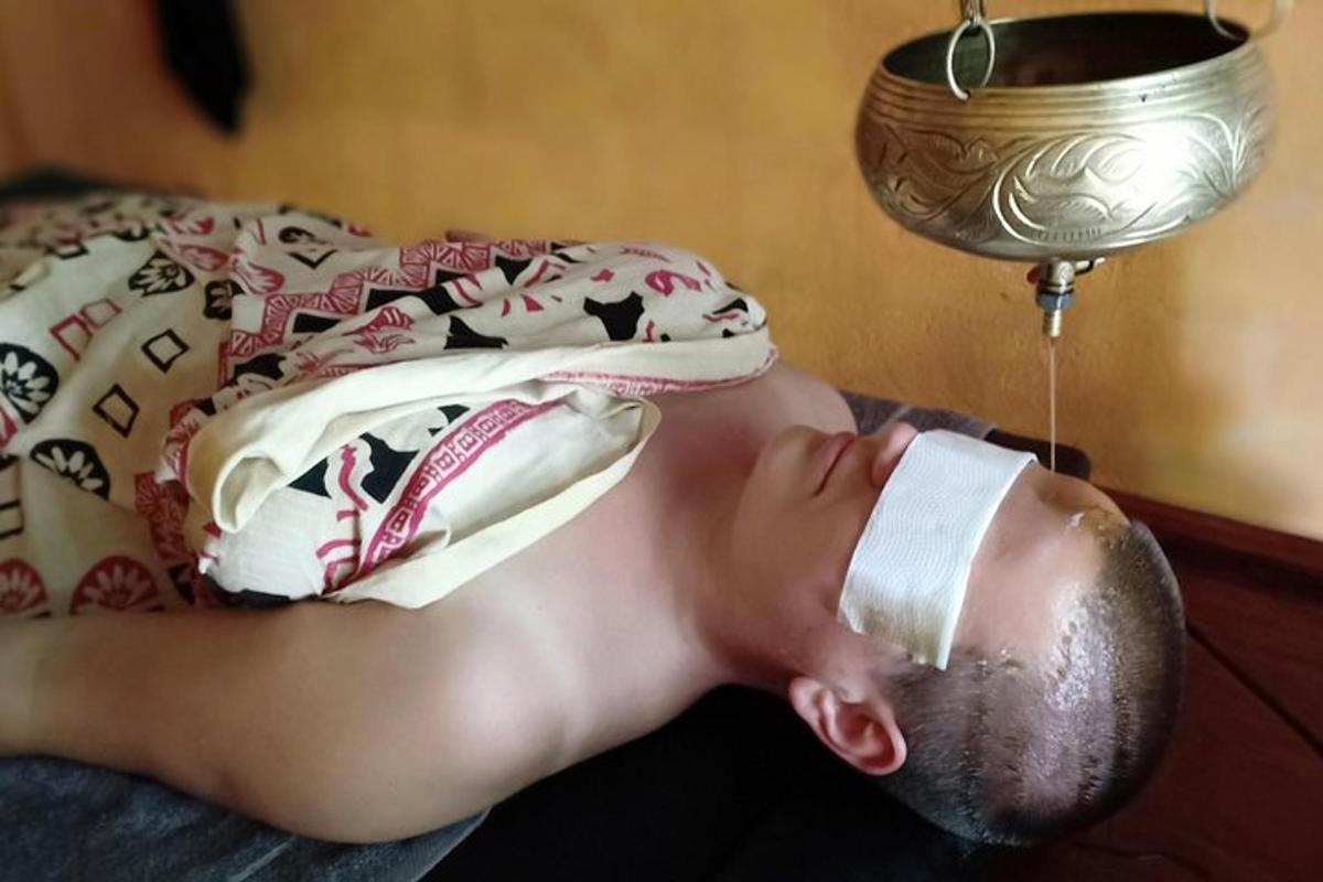 một người đàn ông với đầu băng bó nằm trên giường