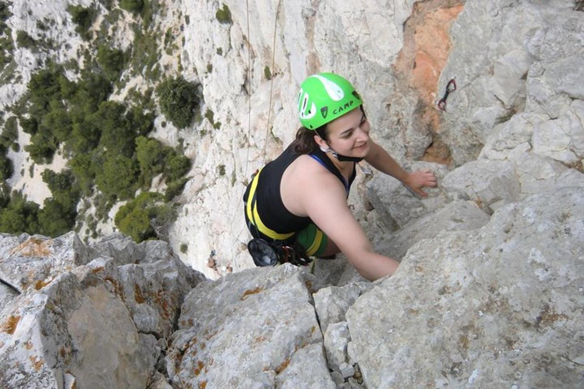 een vrouw in een helm die op een berg klimt