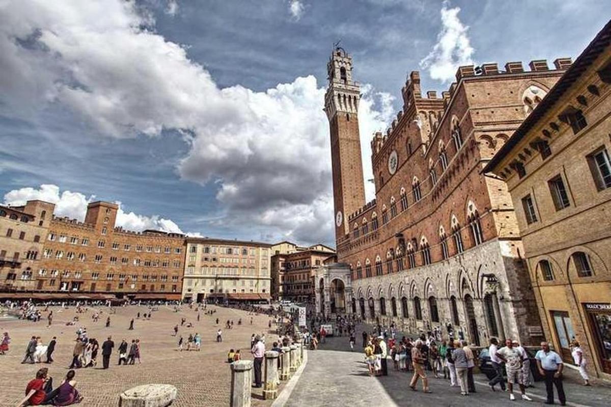 un gruppo di persone che camminano in una città con una torre dell'orologio