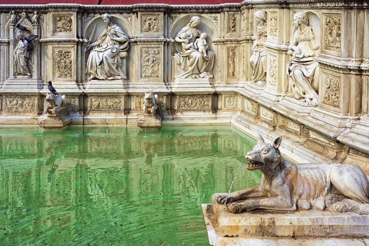 una fontana con la statua di un cane di fronte a un edificio