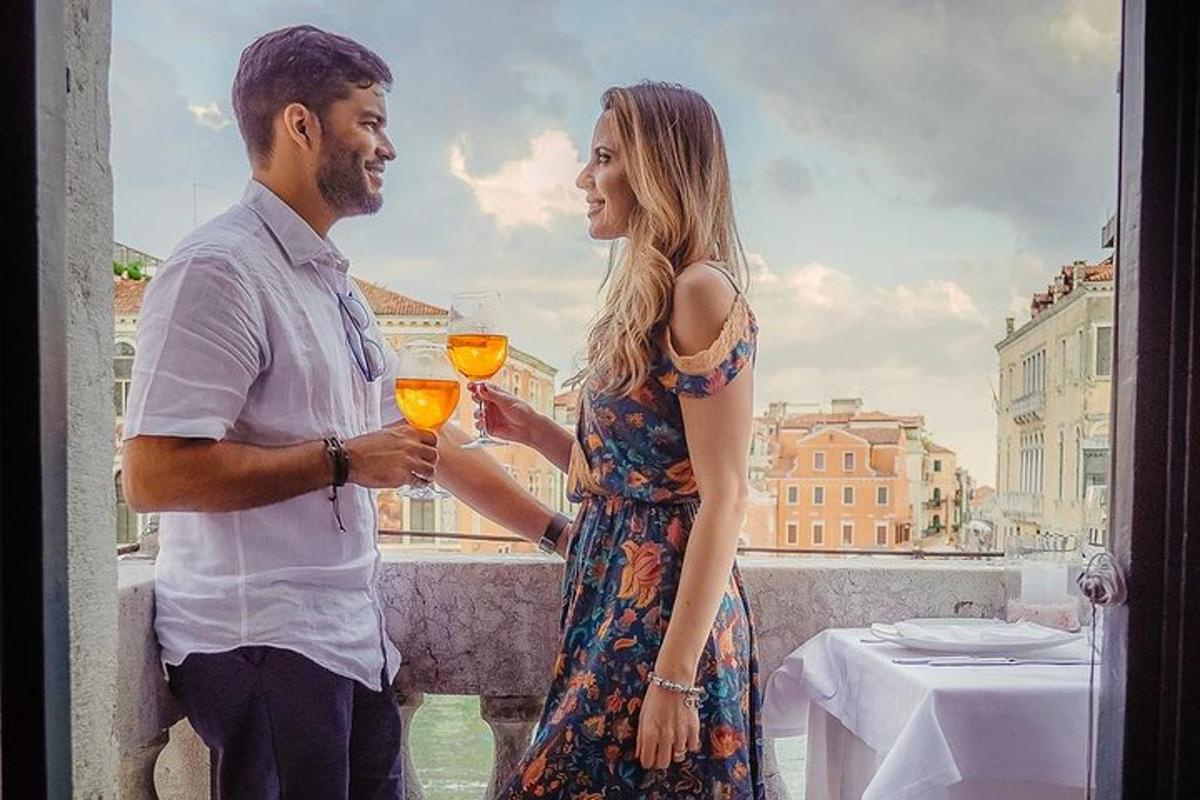 un uomo e una donna in piedi su un balcone con in mano dei bicchieri di vino