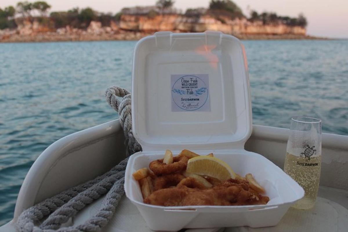 a lunch box with fish and a drink on a boat