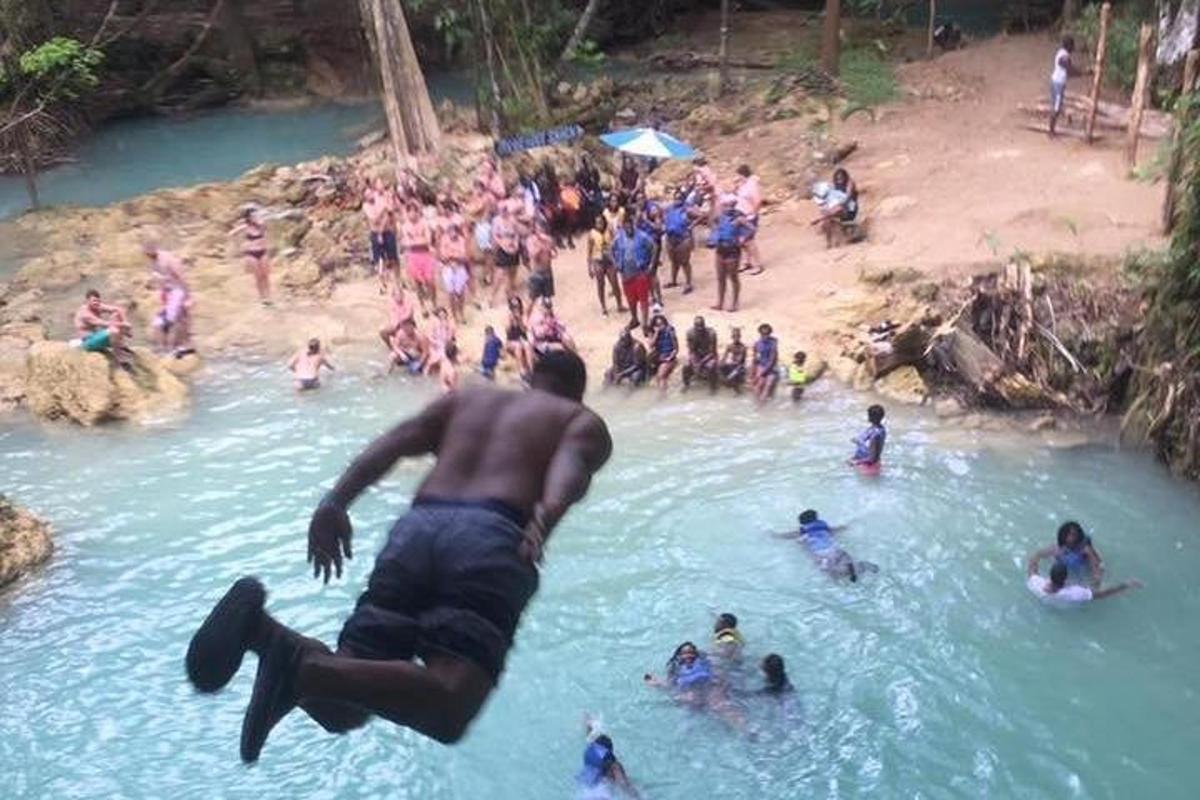 um homem mergulhando em um rio com um grupo de pessoas