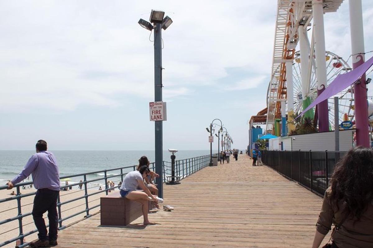 people sitting on a boardwalk next to the ocean