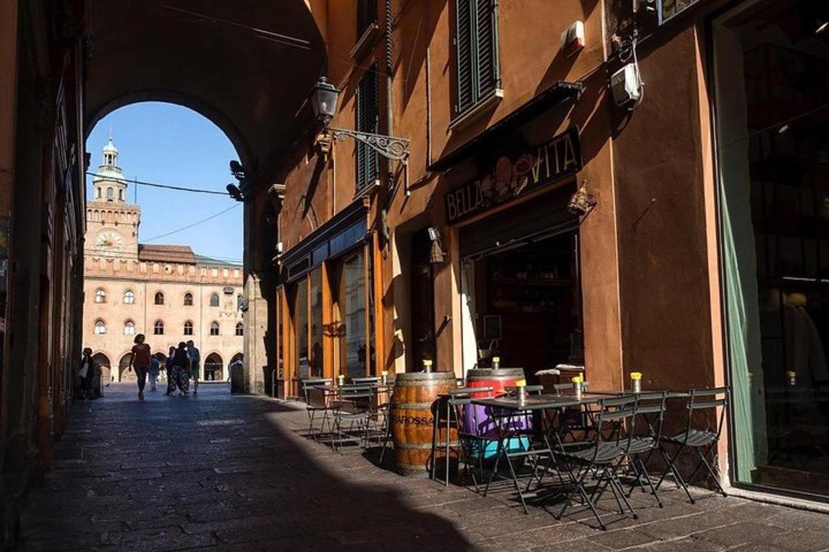 un vicolo con tavoli e sedie e un edificio con una torre dell'orologio