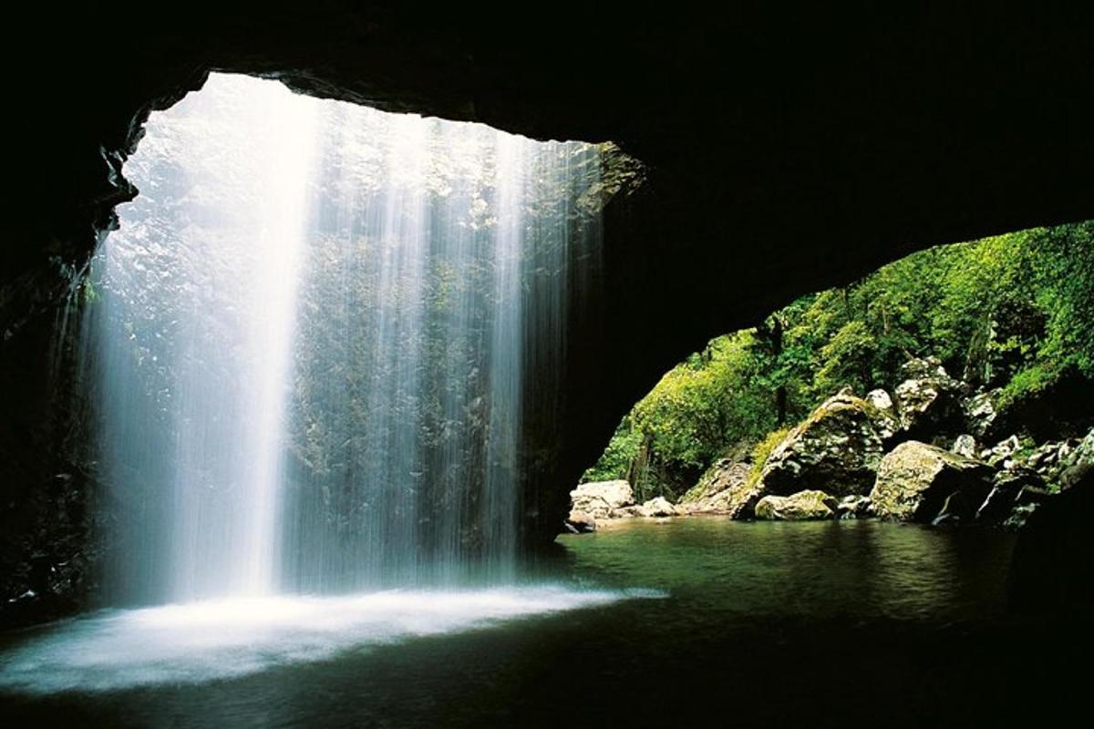 a waterfall in a cave with a body of water